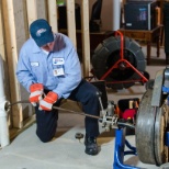 Technician with drain cleaning machine and inline camera