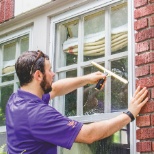 A service professional using the squeegee to cleaning windows.