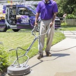 Service Professional using the flat service cleaner to pressure wash a driveway.